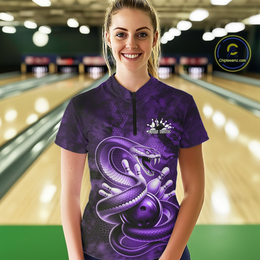Female model wearing a bowling quarter-zip in a bowling lane with purple cobra, bowling ball, and scattered pin artwork.