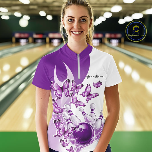 Female model in a white and purple bowling quarter zip featuring butterfly artwork and bowling graphics, front view inside a bowling center