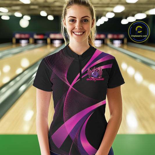 Woman wearing a black and purple bowling shirt with a logo on a bowling alley.