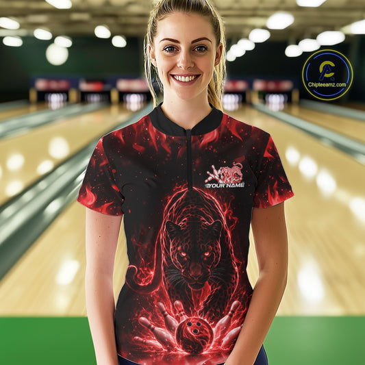 Front view of a female model in a bowling lane wearing a black quarter-zip shirt with glowing red electric panther and bowling ball striking pins illustration.