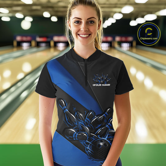 Female model front view in bowling center wearing black and blue quarter zip shirt with flame bowling strike themed artwork