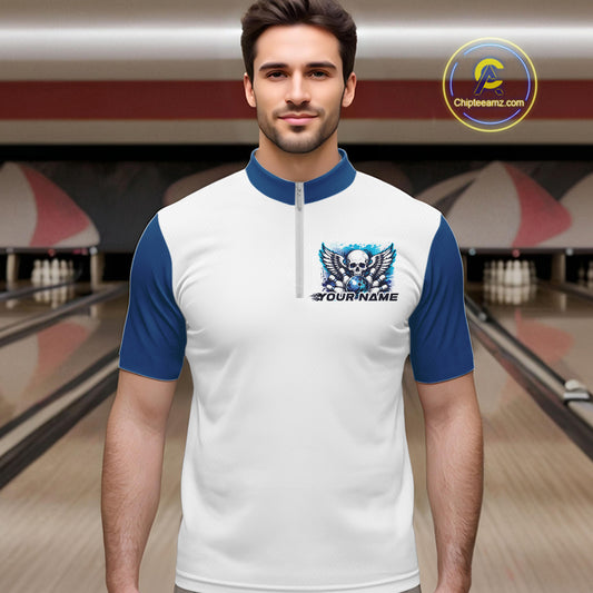 A man stands in a bowling alley wearing a bowling shirt with quarter zip collar, blue skull-themed bowling graphic with black wings, pins, bowling ball