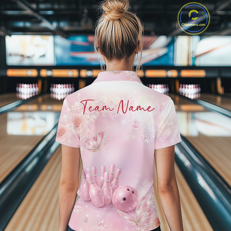 Back view of a female model at a bowling lane wearing a polo shirt featuring pink glitter butterflies, diamonds, bowling pins, and a bowling ball.