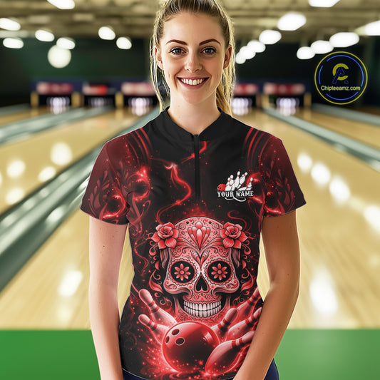 Female model wearing a black and red bowling quarter-zip shirt at a bowling lane with floral sugar skull artwork and bowling-themed accents.