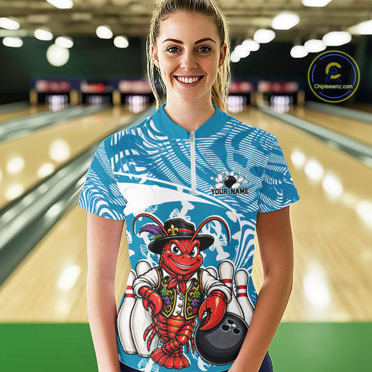 Front view of a happy female model in a bowling alley wearing a blue custom quarter-zip bowling shirt with a funny Cajun crawfish leaning on a bowling ball and a swamp-inspired texture background.