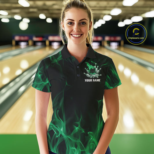 Female model at a bowling lane wearing a black and green bowling polo shirt with scattered bowling pins and fiery bowling action graphics.
