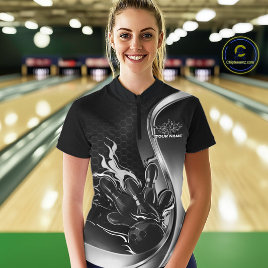 Female model front view at bowling lane wearing black and gray quarter zip shirt with flame bowling ball and pins artwork