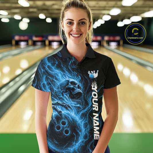 Female model wearing a black bowling polo shirt in a bowling alley featuring a skull clutching a bowling ball surrounded by swirling blue energy flames
