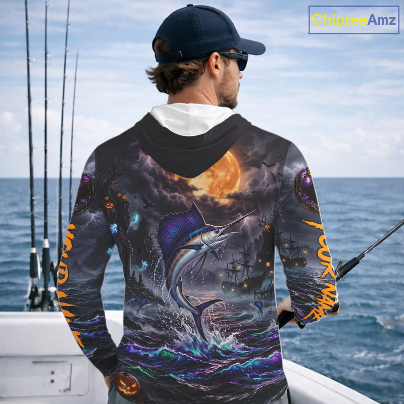 A man wearing a dark navy blue hoodie with a highly detailed, colorful graphic print on the back and sleeves. The print features a marlin jumping from the ocean, a large orange full moon, storm clouds, and pirate ships.