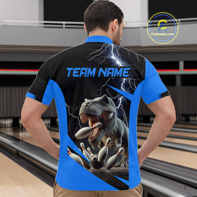 A man viewed from behind wearing a short-sleeve bowling shirt with a large back graphic showing a T-rex eating bowling pins under lightning, with 'TEAM NAME' printed across the upper back. Bowling lanes are visible in the background