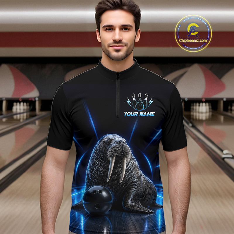Man wearing a black bowling shirt with a walrus design in a bowling alley.
