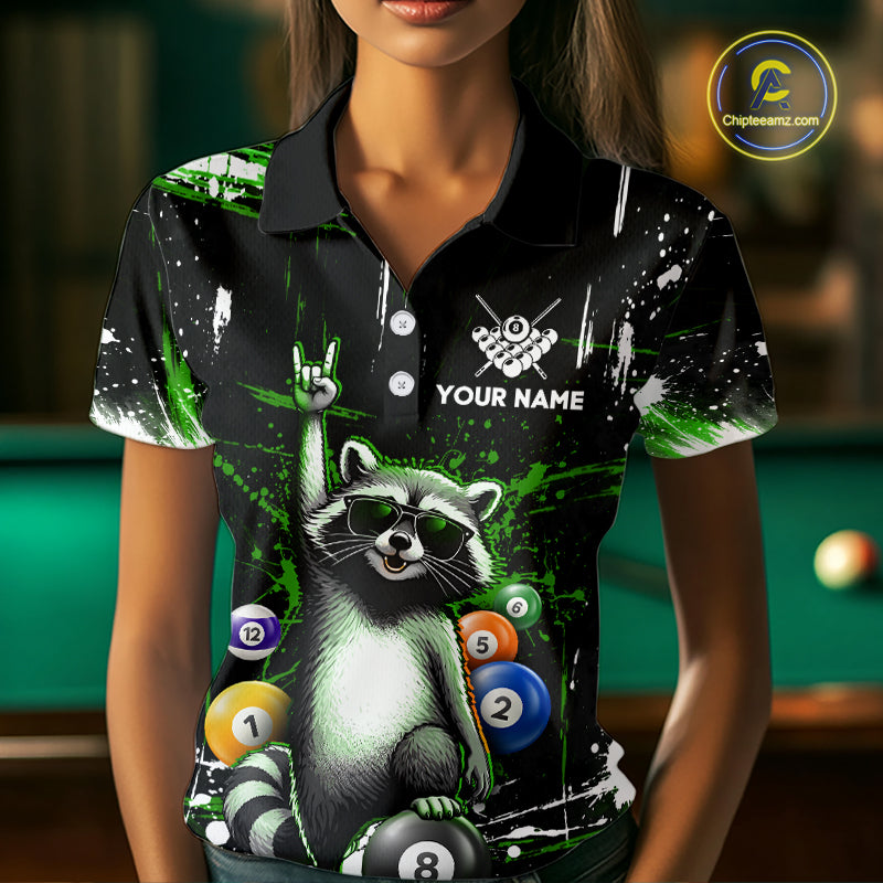 Person wearing a black polo shirt with a raccoon design and pool balls, with a pool table in the background.