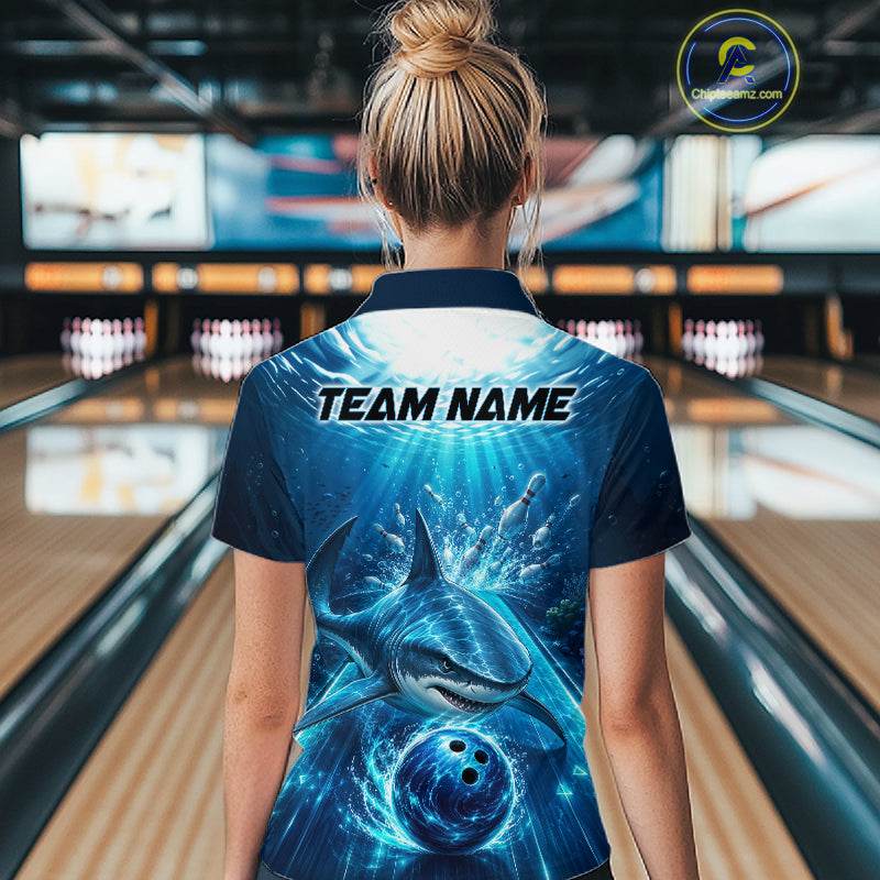 Person wearing a bowling shirt with a shark design and 'TEAM NAME' text in a bowling alley.