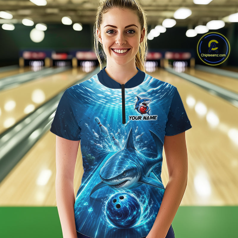 Person wearing a blue bowling shirt with shark design in a bowling alley.