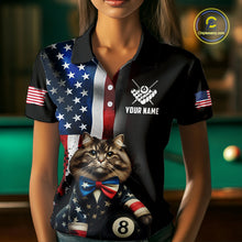 Load image into Gallery viewer, A front view of a custom black billiards polo shirt worn by a female model holding a pool cue. The shirt features a distressed US flag design on one side and a cartoon cat in a vest with its paw on an 8-ball on the front. A 'YOUR NAME' text placeholder is positioned below a crossed pool cues icon. The background is a blurred billiards room with a green pool table.