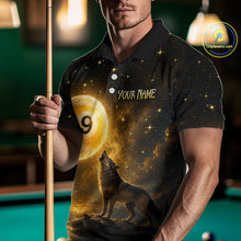 Load image into Gallery viewer, A man wearing a custom black polo shirt with a gold and yellow cosmic wolf design, holding a pool cue in a dimly lit pool hall. The shirt features a starry night sky, a large golden billiard ball with the number 9, and a howling wolf.