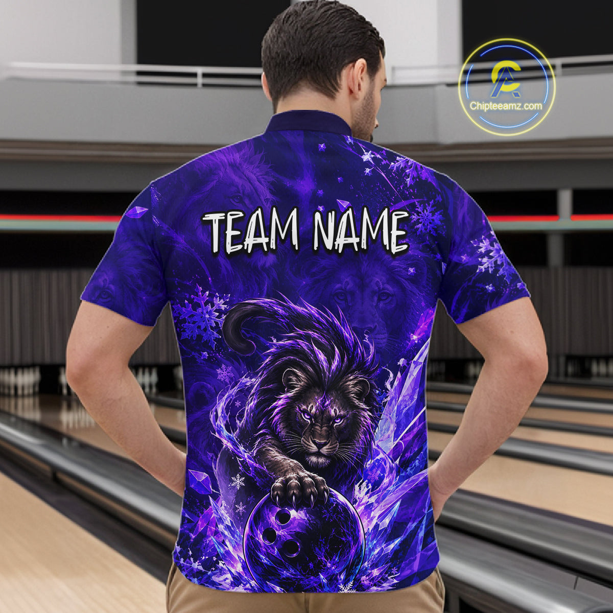 A man viewed from behind wearing a short-sleeve bowling shirt with a purple and blue cosmic lion graphic and the text 'TEAM NAME' on the back. The background shows bowling lanes