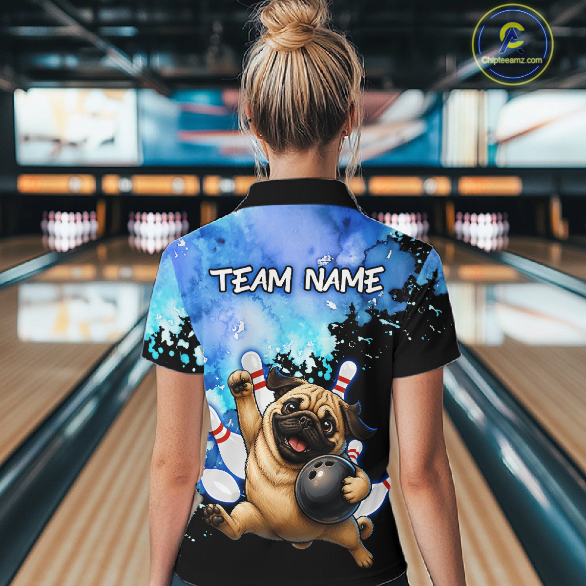 A woman viewed from behind wearing a custom bowling-themed short-sleeve polo shirt with a printed pug holding a bowling ball and the text 'TEAM NAME' on the back, set against a bowling alley background.