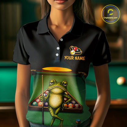 A woman wearing a black short-sleeve polo shirt with a custom graphic print of a frog playing pool and the text 'YOUR NAME'. The background is a blurred green billiards table.