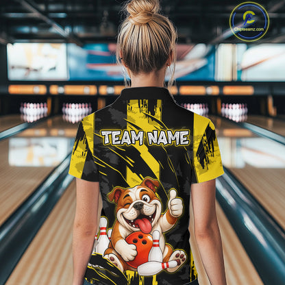 Female model wearing a custom black yellow bulldog bowling polo shirt back view displaying the personalized team name above a playful cartoon bulldog graphic at the bowling alley