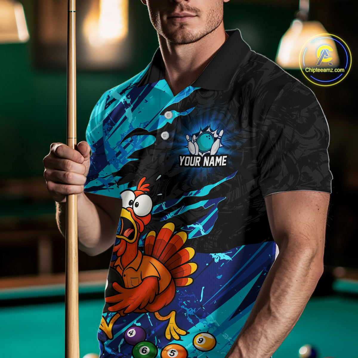A man wearing a custom printed polo shirt with a cartoon turkey and pool balls, holding a pool cue in a dimly lit billiards room. The shirt features a black collar and upper section, transitioning to a cyan and black splatter pattern with a red and orange turkey graphic and white placeholder text reading 'YOUR NAME'.