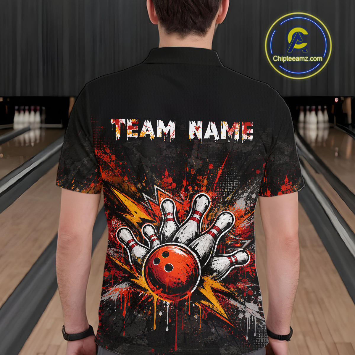 A man viewed from behind wearing a black short-sleeve bowling-themed polo shirt with a large graphic of a hand holding a red bowling ball and the text 'TEAM NAME' across the upper back. Bowling lanes are visible in the background