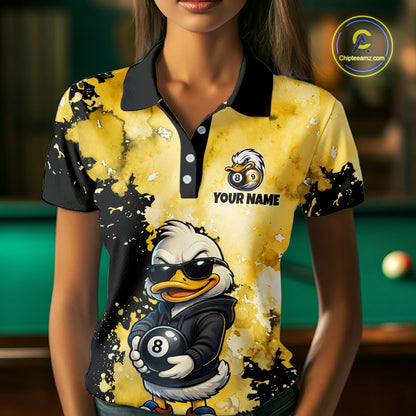 A woman wearing a custom yellow and black polo shirt featuring a cartoon duck wearing sunglasses and holding an 8-ball, with the text 'YOUR NAME' on the chest. The background shows a blurred pool table.