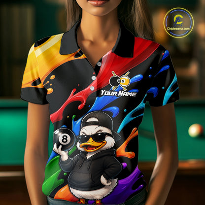 A woman wearing a short-sleeve polo shirt with a colorful abstract paint-splatter design and a cartoon duck character holding an 8-ball. The shirt has a black collar and the text 'YOUR NAME' on the chest