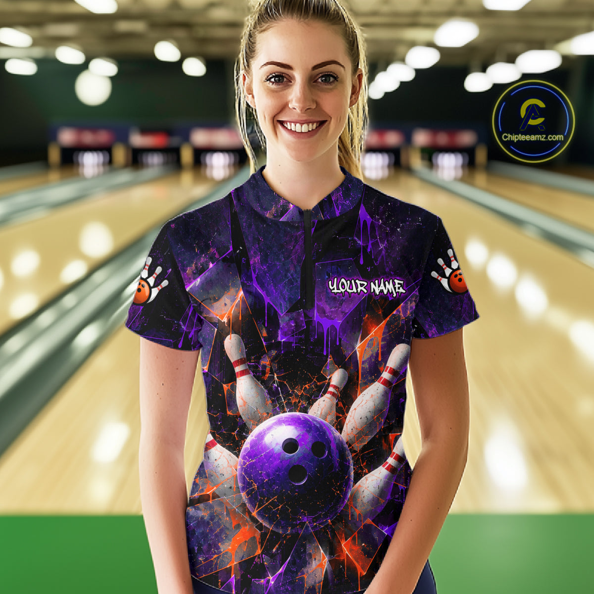 A woman standing in a bowling alley wearing a short-sleeve bowling-themed t-shirt with a purple and black cosmic design, bowling pins, and a purple bowling ball graphic. The shirt has 'YOUR NAME' printed on the chest.