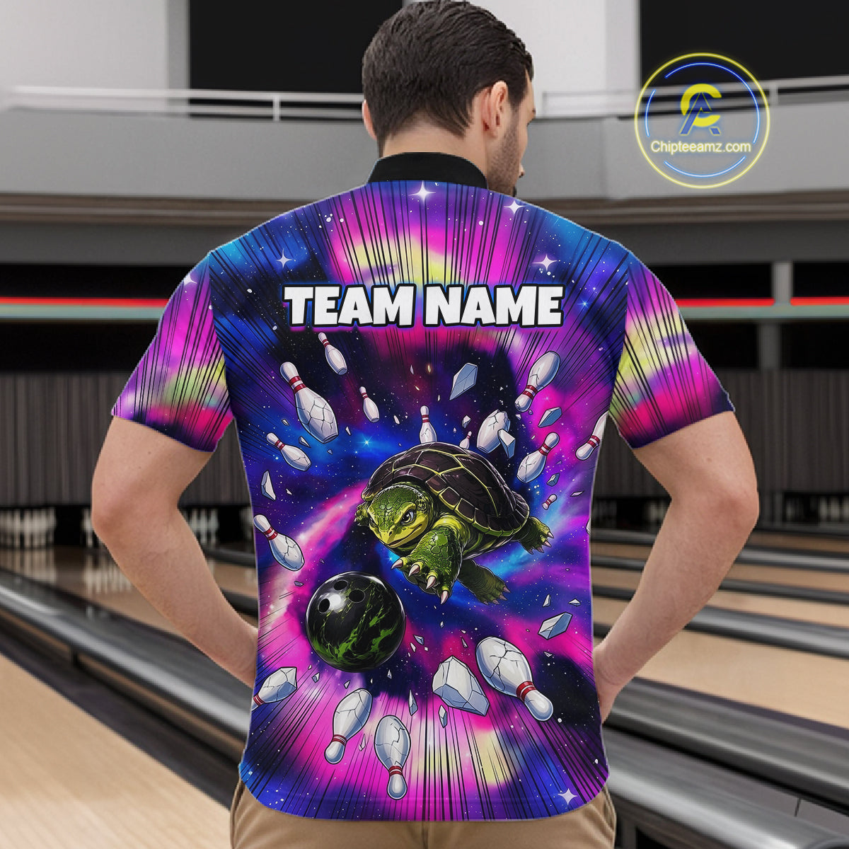 Person wearing a colorful bowling shirt with a turtle design and 'TEAM NAME' text in a bowling alley.