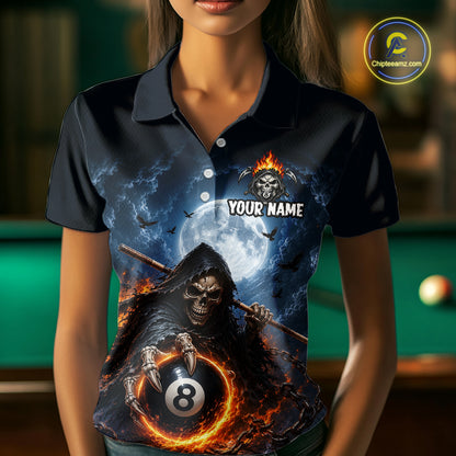 A woman wearing a dark navy polo shirt with a detailed graphic print of a grim reaper holding a flaming 8-ball in front of a full moon and bats. The shirt features a customizable placeholder text 'YOUR NAME' and a skull flame logo on the chest.