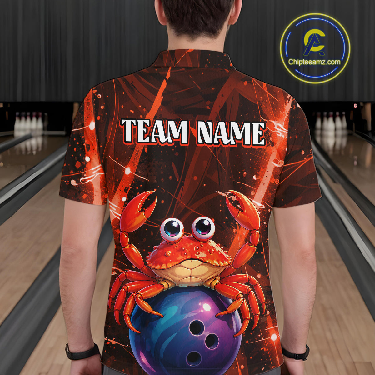 Person wearing a shirt with a cartoon crab and bowling ball design in a bowling alley.