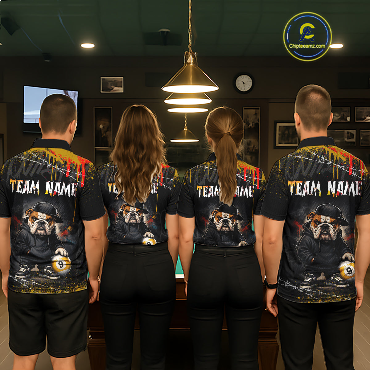 Four people standing with their backs to the camera in a dimly lit indoor venue, wearing matching black short-sleeve team shirts with a large bulldog graphic and 'TEAM NAME' text on the back.