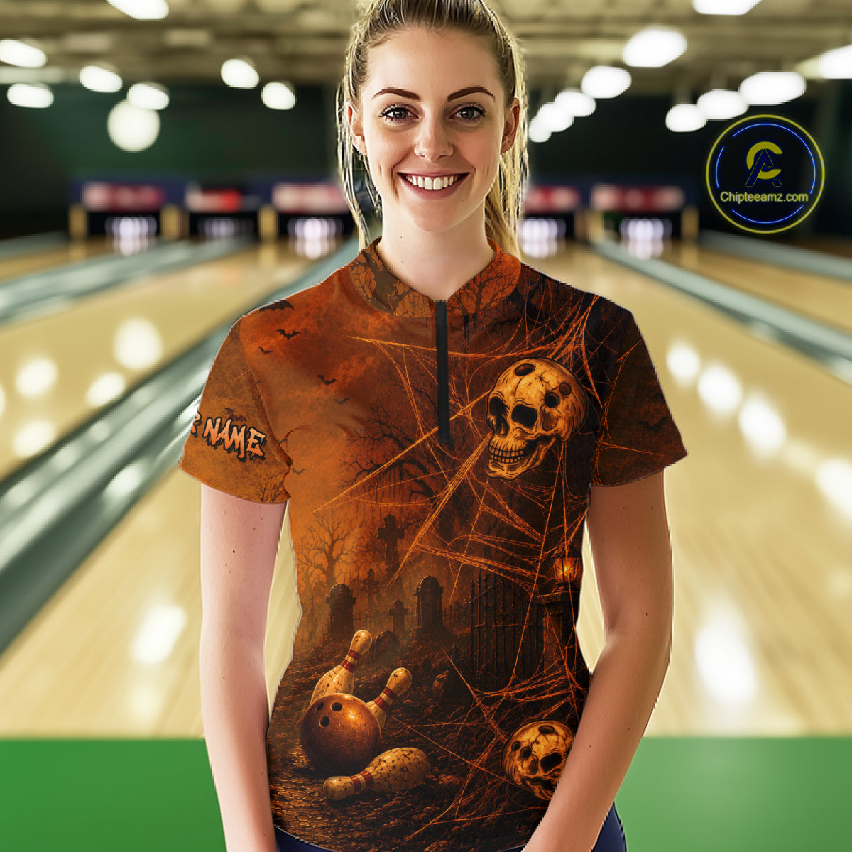 A woman standing in a bowling alley wearing a short-sleeve collared bowling shirt with a dark brown and black Halloween-themed graphic print featuring skulls, bones, and cobwebs. The shirt has a mock neck and a black zipper.