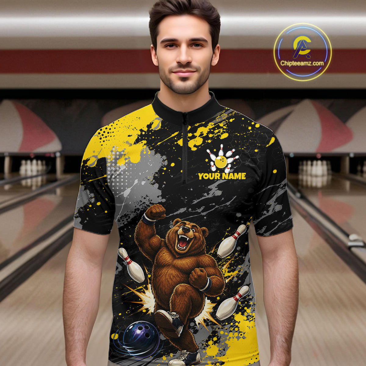 A man wearing a custom bowling-themed short-sleeve shirt with a black and yellow paint splatter design, a cartoon bear bowling, and 'YOUR NAME' text on the chest. The background shows blurred bowling lanes