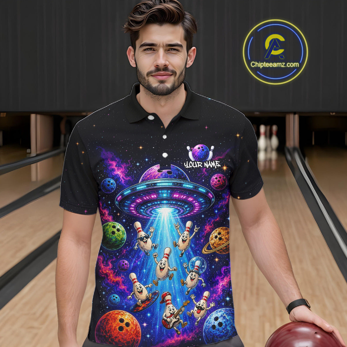 Man wearing a black polo shirt with a colorful alien design in a bowling alley.