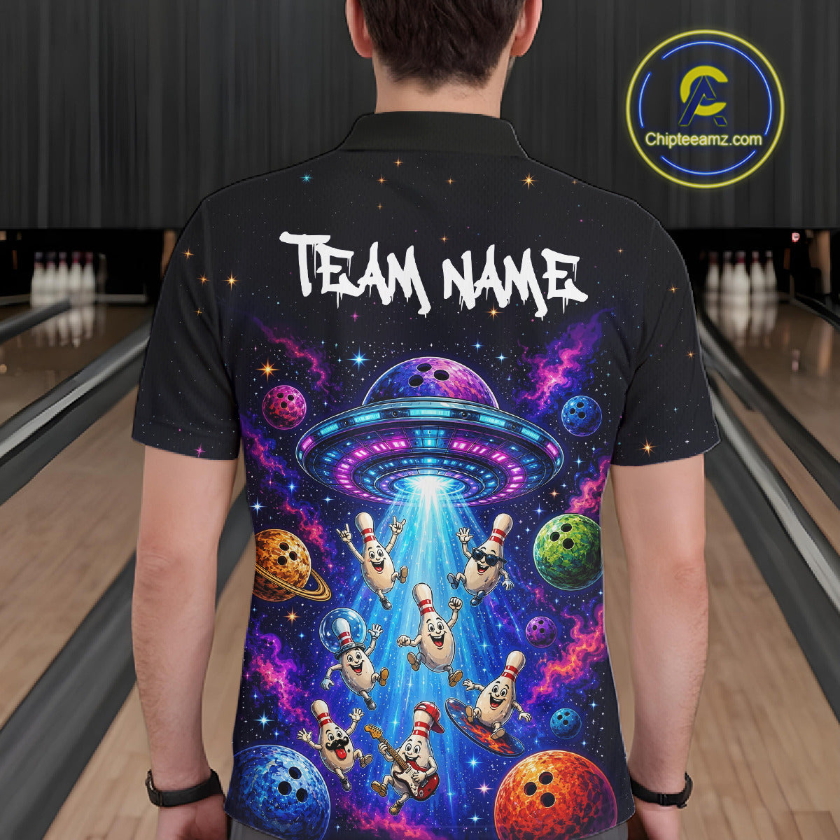 Person wearing a black bowling shirt with a colorful UFO and bowling ball design, standing in a bowling alley.