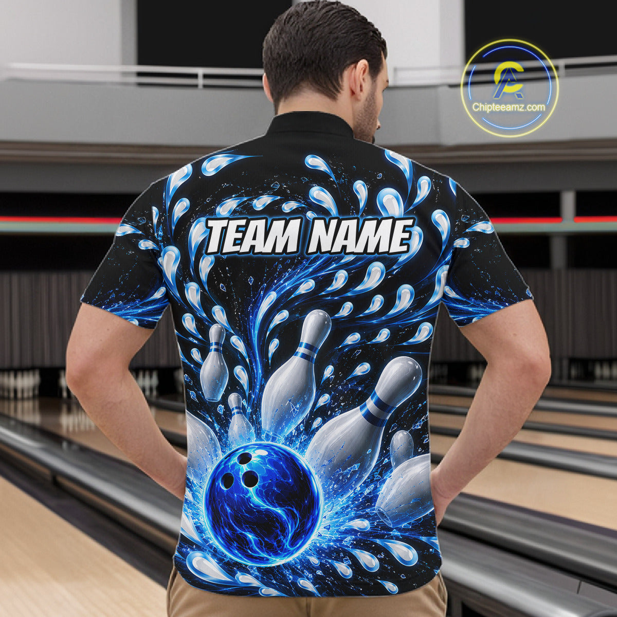 Person wearing a bowling-themed shirt with a blue ball and pins design in a bowling alley.