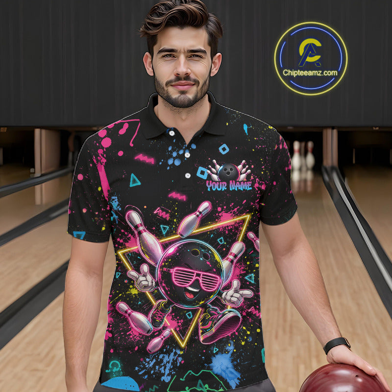 A man wearing a black short-sleeve bowling-themed graphic polo shirt with a cartoon bowling ball character, neon paint splatters, and the text 'YOUR NAME' on the chest. 
