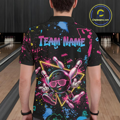 A person viewed from behind wearing a black short-sleeve bowling-themed graphic shirt with colorful paint splatters, a bowling pin character, and the text 'TEAM NAME'. Bowling lanes are visible in the background