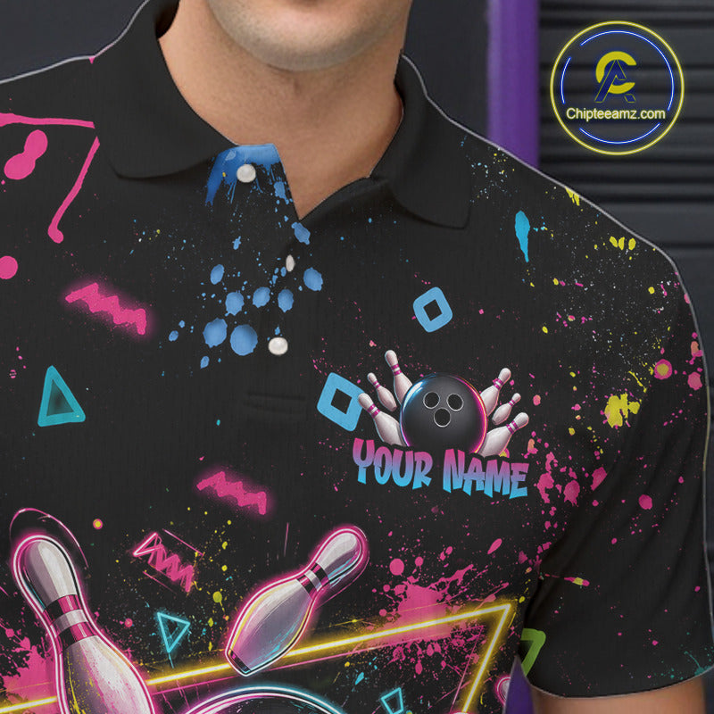 A close-up of a person wearing a black short-sleeve polo shirt with a colorful bowling-themed graphic print. The design includes neon paint splatters, bowling pins, a bowling ball, and the text 'YOUR NAME' in pink and blue.
