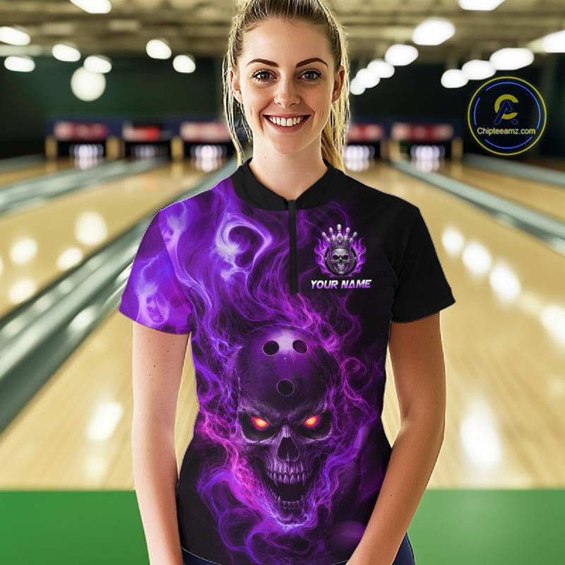Woman wearing a black bowling quarter zip shirt featuring a flaming skull with glowing orange eyes, purple smoke effects, and custom “YOUR NAME” text
