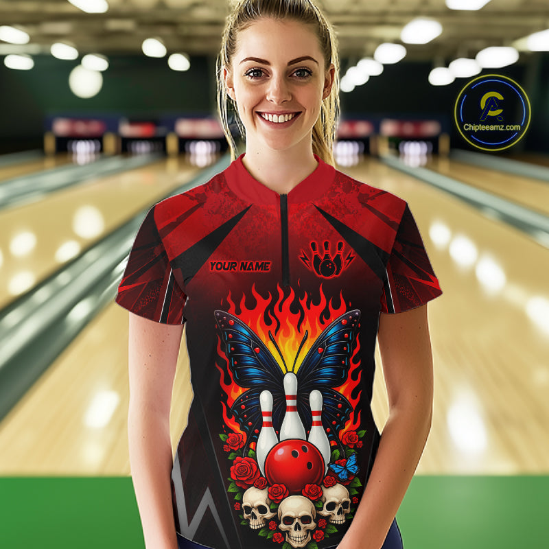 Woman wearing a red and black bowling quarter zip shirt featuring flaming bowling pins, a red bowling ball, a blue butterfly, roses, skulls, and custom player name text.