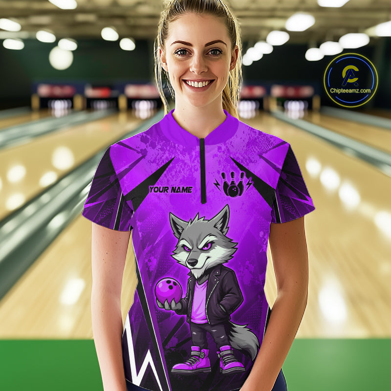 Woman wearing a purple and black bowling quarter zip shirt featuring a gray wolf mascot holding a purple bowling ball, with custom player name text.