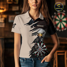Load image into Gallery viewer, Person wearing a beige and black darts polo featuring a bald eagle, torn-flag graphics, dartboard designs, and custom team text.