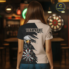 Load image into Gallery viewer, Person wearing a beige and black darts polo featuring a bald eagle, torn-flag graphics, dartboard designs, and custom team text.