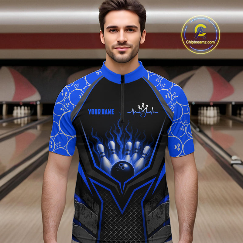 Man wearing a blue and black bowling shirt with a bowling ball design in a bowling alley.