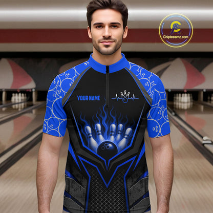 Man wearing a blue and black bowling shirt with a bowling ball design in a bowling alley.
