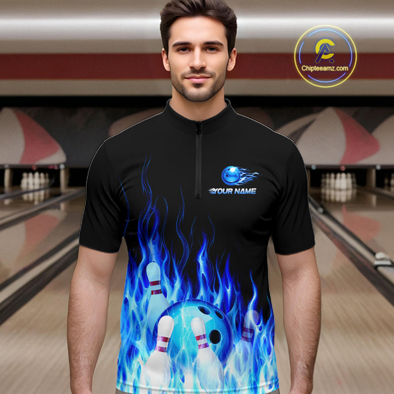 Man wearing a black bowling shirt with blue flame design in a bowling alley.