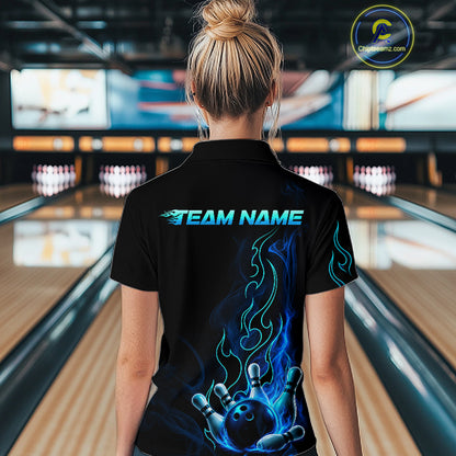 A woman viewed from behind wearing a black short-sleeve bowling polo shirt with a custom blue and teal flame graphic and 'TEAM NAME' text on the back, standing in a bowling alley.